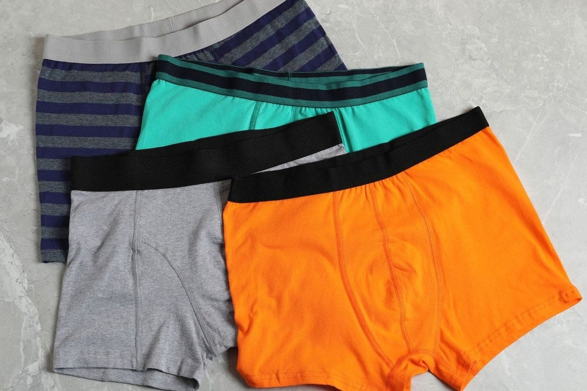 Four pairs of men's boxer briefs in different colors on a surface.